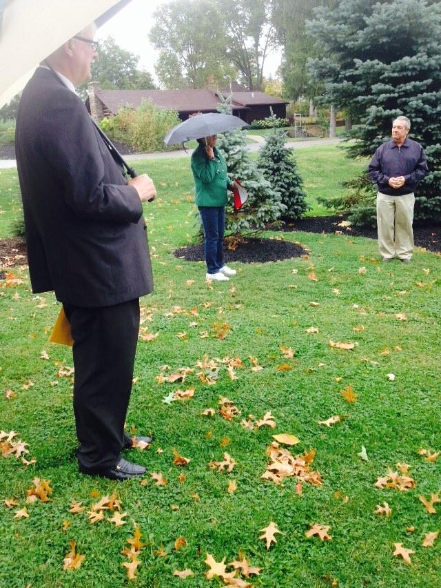 People holding umbrellas attend dedication at park to Peg Castina